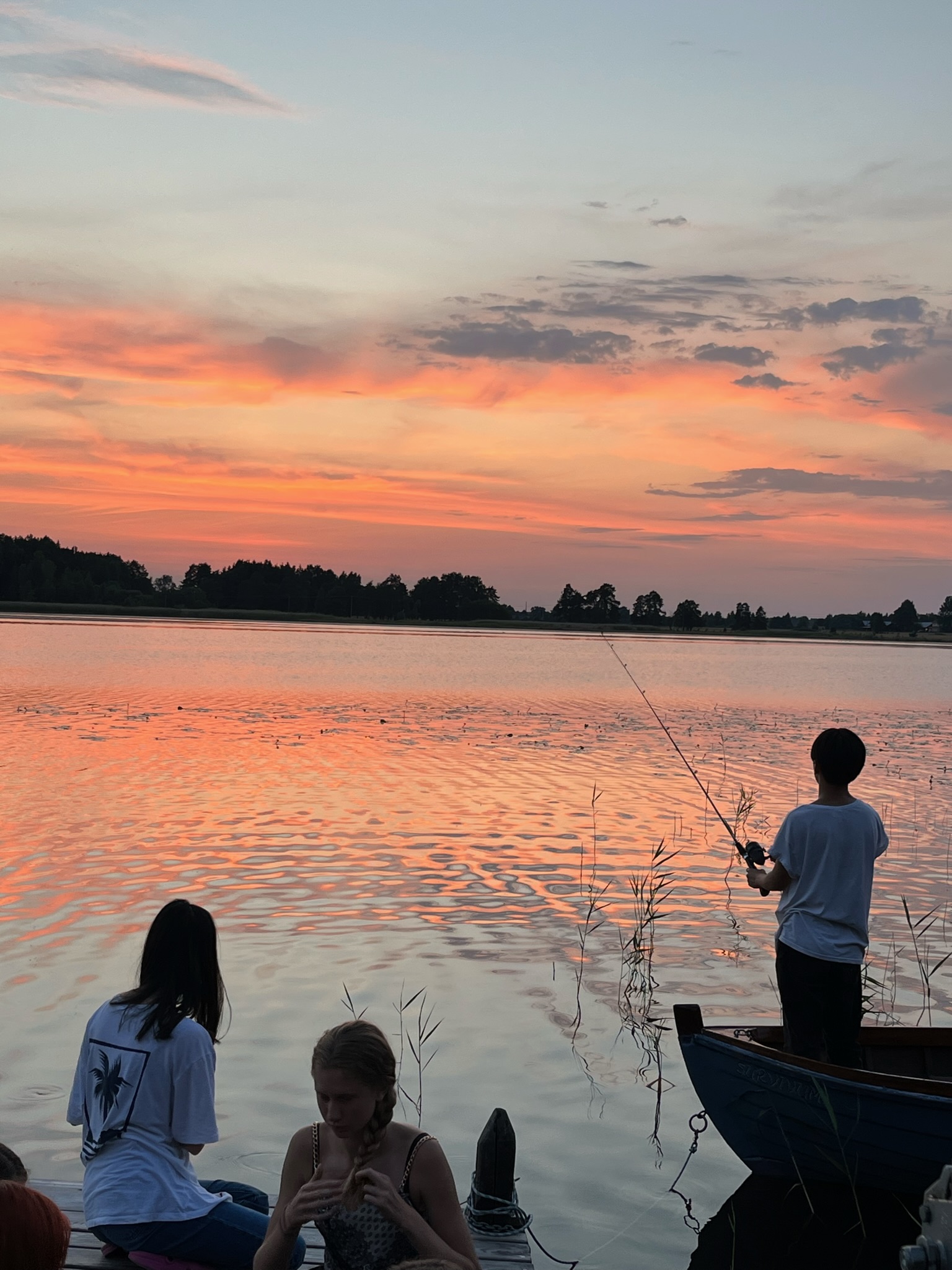 Fiske från bryggan och båten vid solnedgången