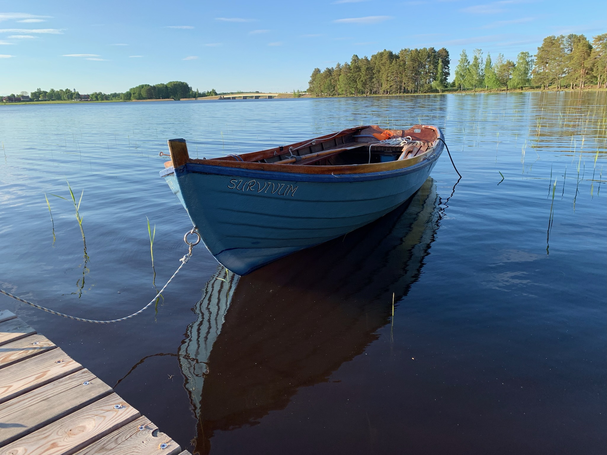 Blå träbåt förtöjd vid bryggan