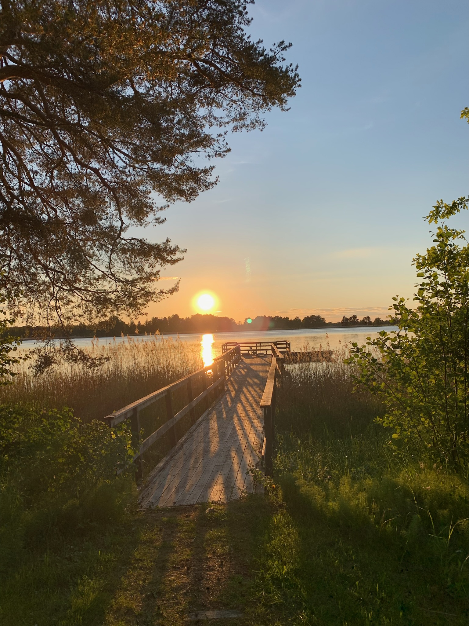 Solnedgång över älven sedd från stranden vid bryggan