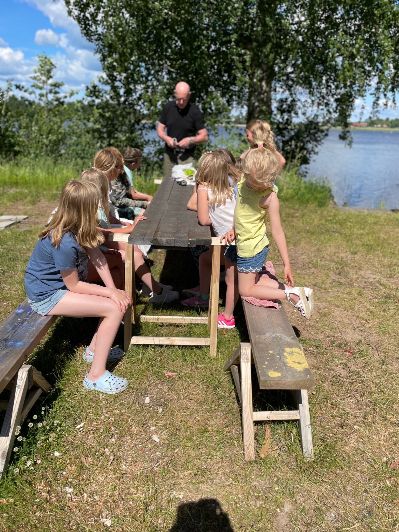 Deltagare samlas kring ett bord på gräsmattan vid älven