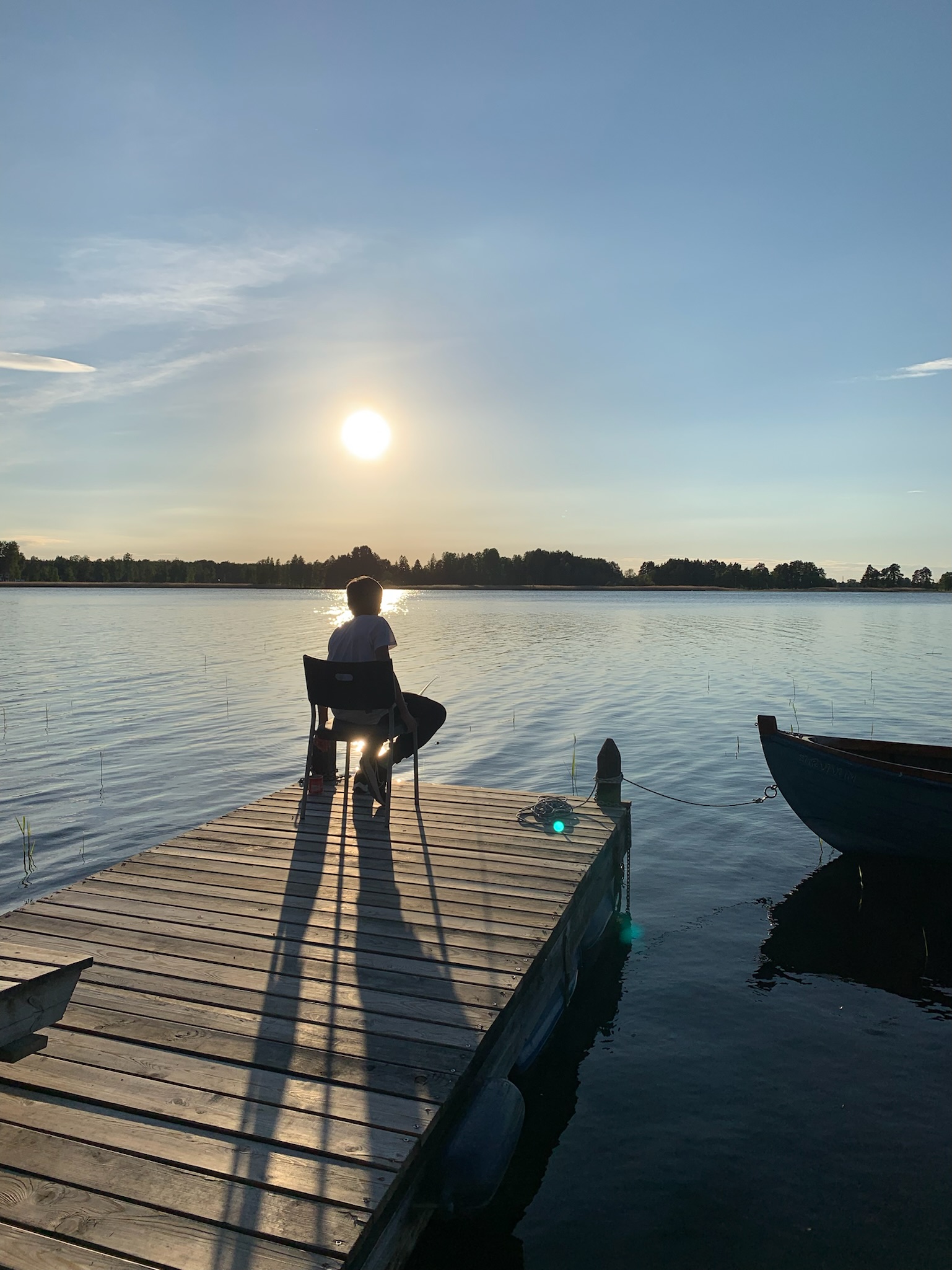 En person fiskar från bryggan i kvällssolen